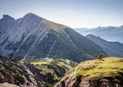 Eine Gruppe von Menschen steht auf dem Tiroler Berg, genießt die atemberaubende Aussicht auf das Karwendel und wandert entlang des Höhenwegs.